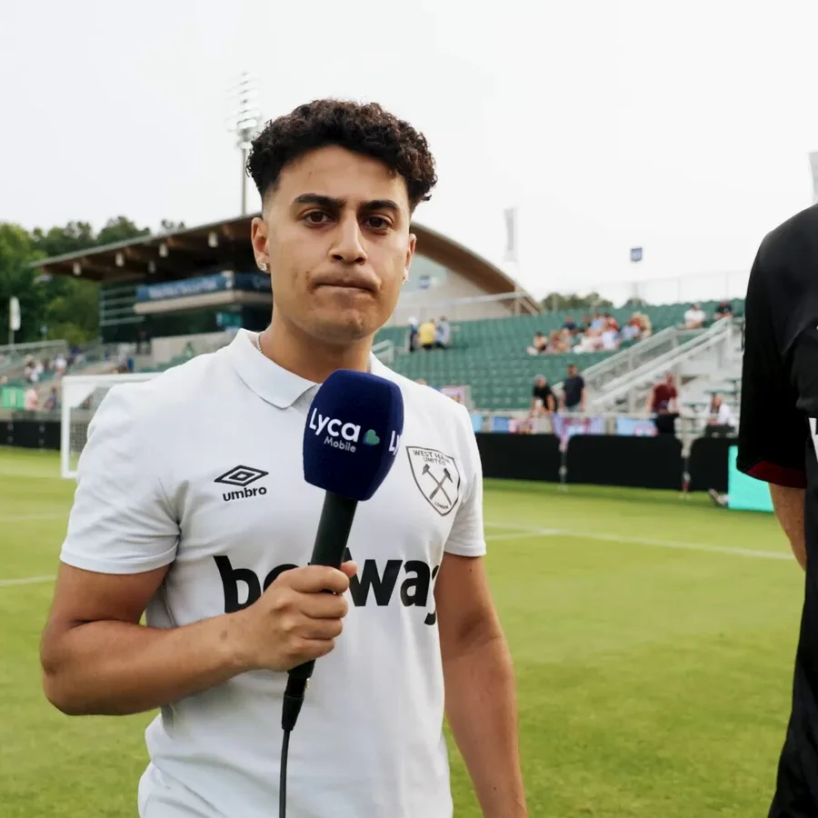 Josh Birdi holding a microphone in a West Ham shirt
